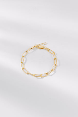 A gold-plated bracelet with a sleek, chain-link design laid out on a white surface.