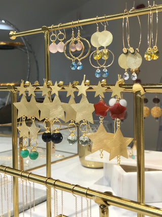 Beautiful brushed gold star earrings and pendants displayed on a delicate gold rail