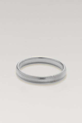 A silver-toned metal bangle bracelet with a textured, ribbed snake-skin style pattern, shown on a neutral light gray background.