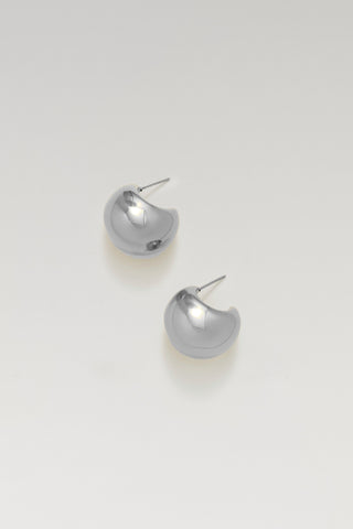 A pair of polished silver crescent-shaped stud earrings on a clean, light gray background.
