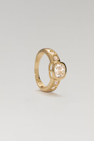 Mara ring, gold plated, standing at an angle to show the cushion-cut centre stone and band-set side stones
