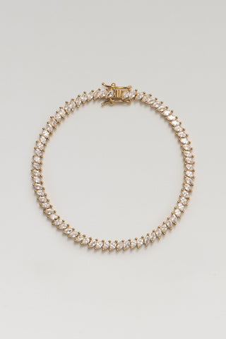 Nico tennis bracelet, gold plated, lying in a circle with its box clasp and angled marquise-cut cubic zirconia