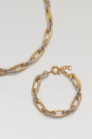 Allegra necklace and Allegra bracelet, gold and rhodium plated, laid together on a pale surface