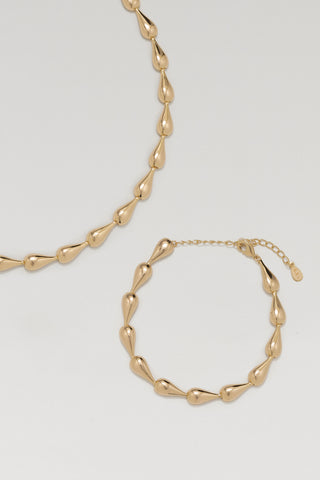 Riva necklace and Riva bracelet, gold plated, laid together showing the hollow teardrop links