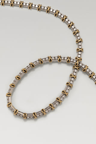 Renata necklace and Renata bracelet, rhodium and gold plated, laid overlapping on a pale surface
