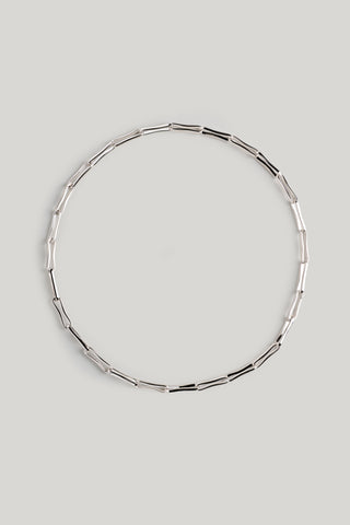 A silver-toned geometric link chain necklace arranged in a perfect circle on a light gray background.
