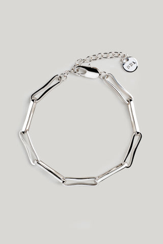 A silver-toned geometric link bracelet with a lobster clasp and a small circular charm, displayed on a neutral light gray background.