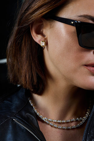 Model's ear and neck in sunglasses wearing a bezel-set square stud and the two-tone Renata necklace in two rows