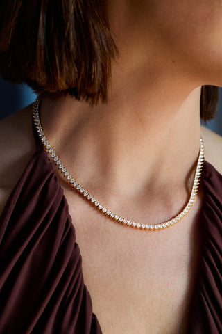Vida tennis necklace, gold-tone, worn at the collarbone over a burgundy halter top