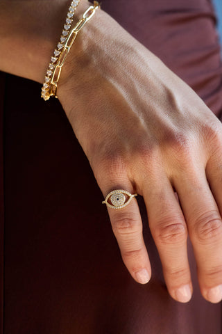 Gold plated Protective Eye ring on the hand, at the hip of a burgundy dress, with a paperclip bracelet and a tennis bracelet