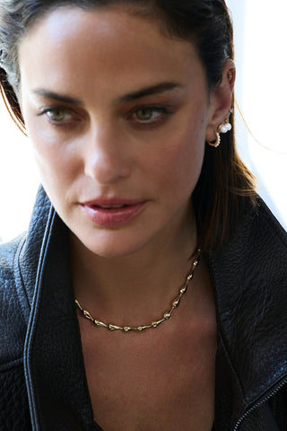 Riva necklace, gold plated, worn at the collarbone with a black leather jacket and white drop earrings