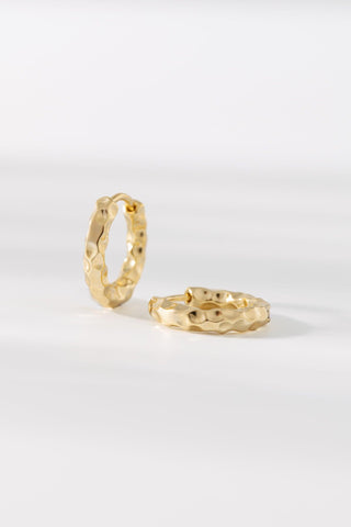 Chase gold huggie earrings with a polished finish on a white background