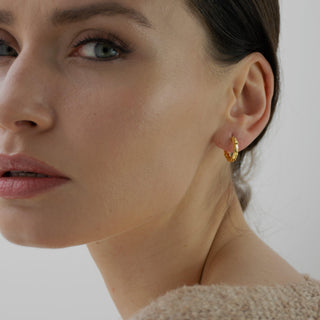 Chase gold huggie earrings worn on the ear with a classic rounded silhouette