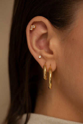 Nova gold stud earrings worn on the ear with a starburst silhouette