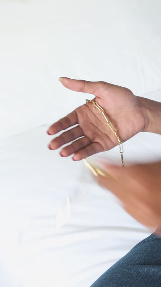 video of a model holding the mini and original Delphine gold bracelets 