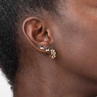 Remy gold stud earrings worn on the ear with a minimal design