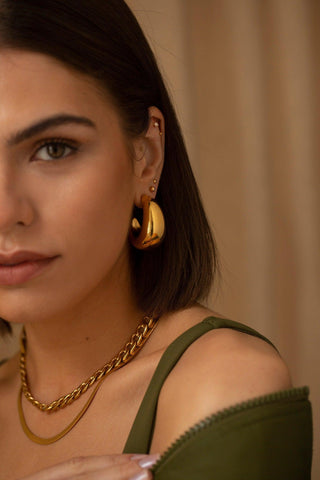 Roz gold hoop earrings worn on the ear with a classic rounded silhouette