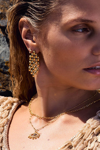 Vivienne Earrings by One Dame Lane, sculptural woven matte gold drop earrings worn on model with textured gold finish.